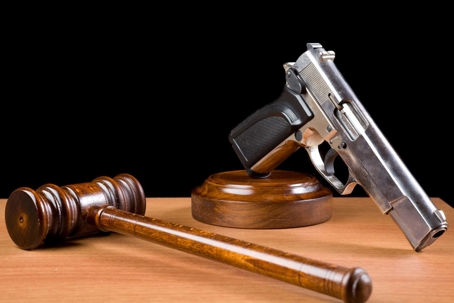 Wooden Gavel And Handgun On Table